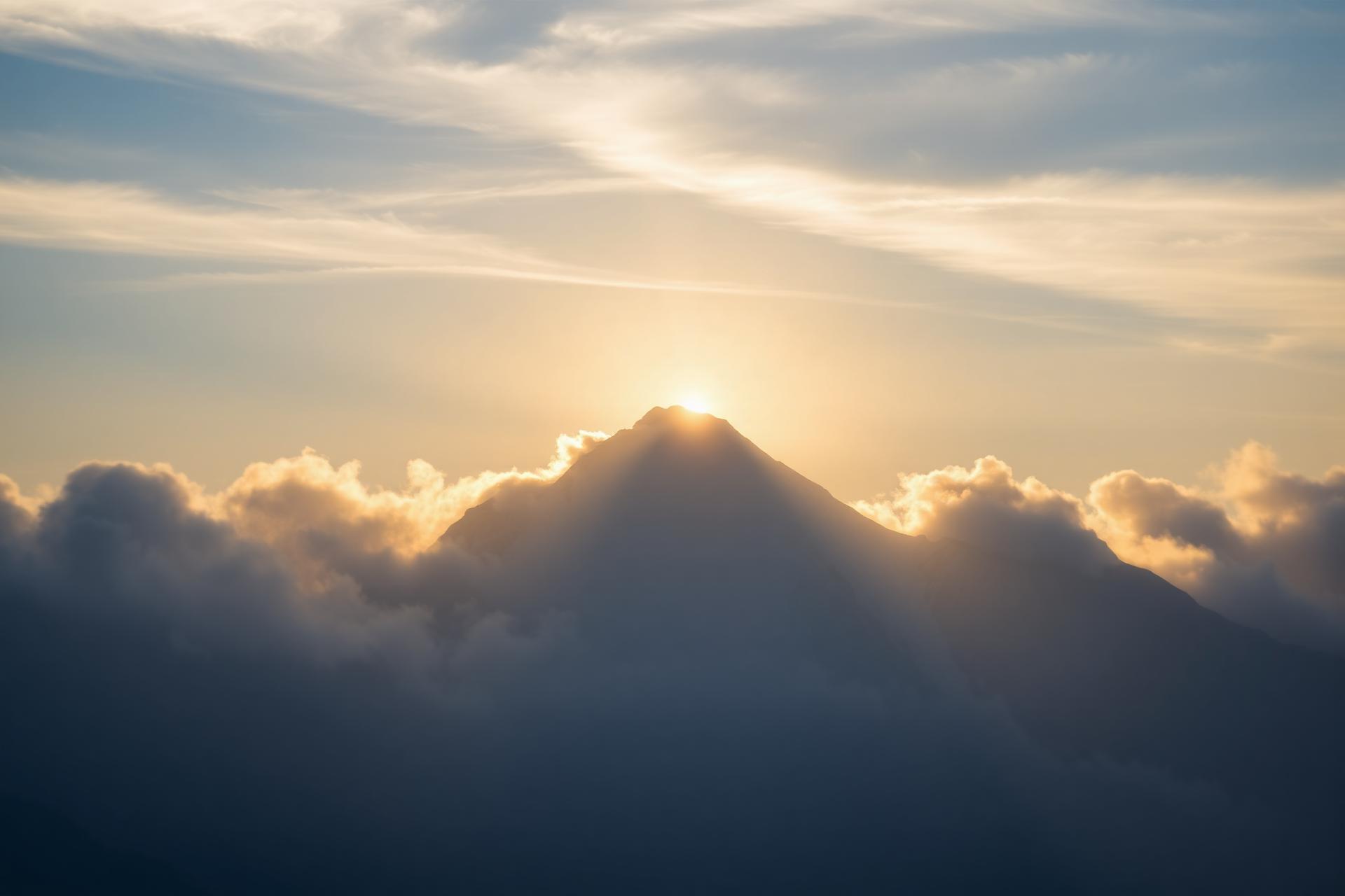 Snow-capped mountain rising through soft golden clouds