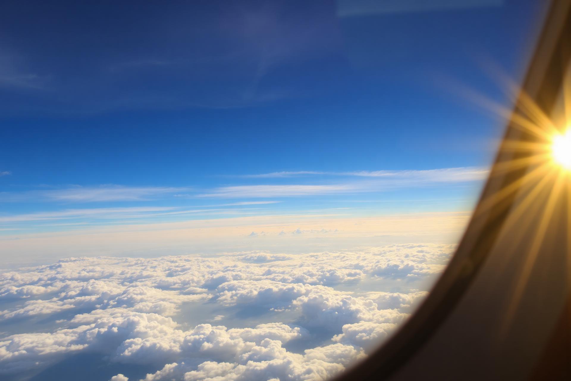 View from an airliner window above a golden cloudscape